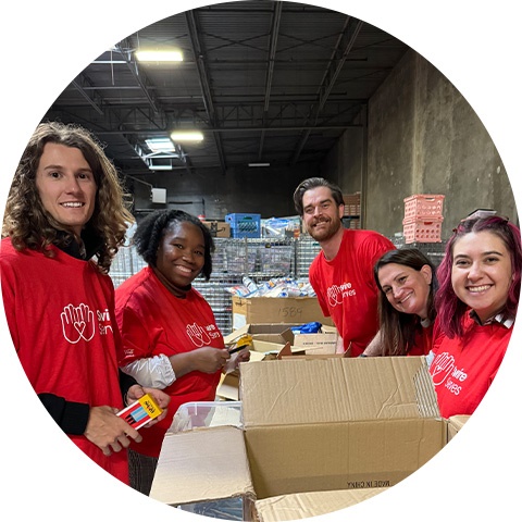 Group of volunteers in red shirts packing boxes in a warehouse